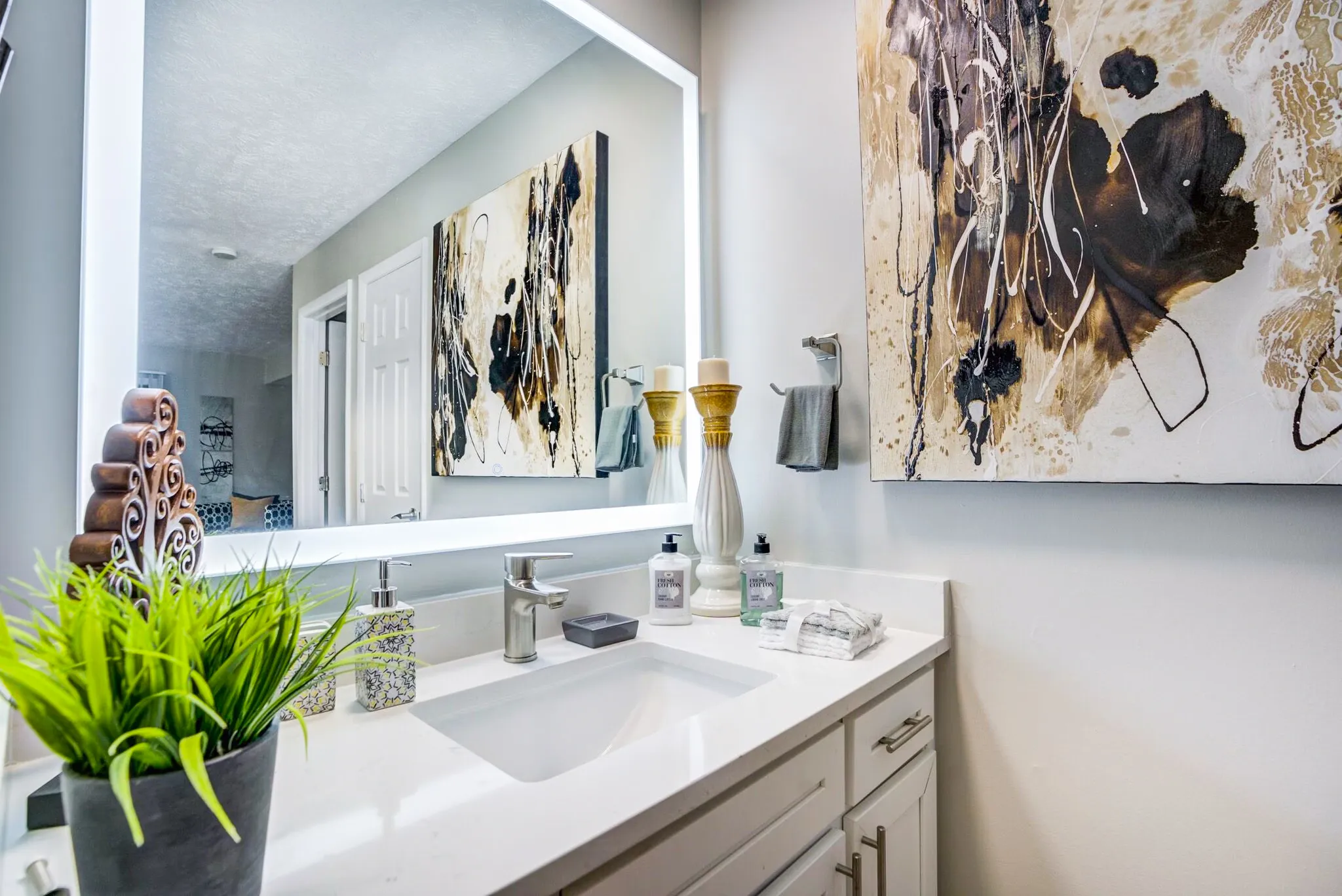 Bathroom, white quartz countertops, large framed mirror, wall-mounted artwork