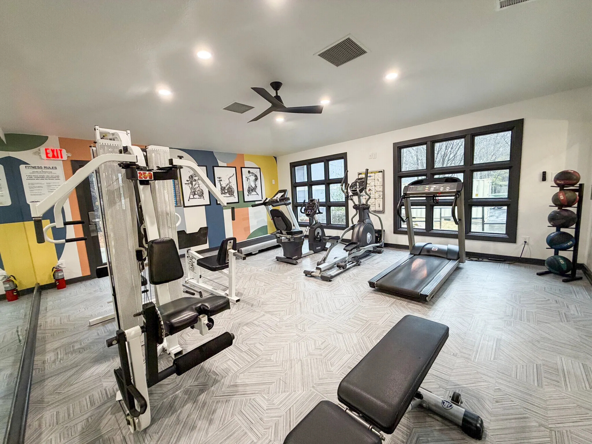 Fitness center, cardio equipment, strength training machines, wood-style plank flooring, ceiling fan