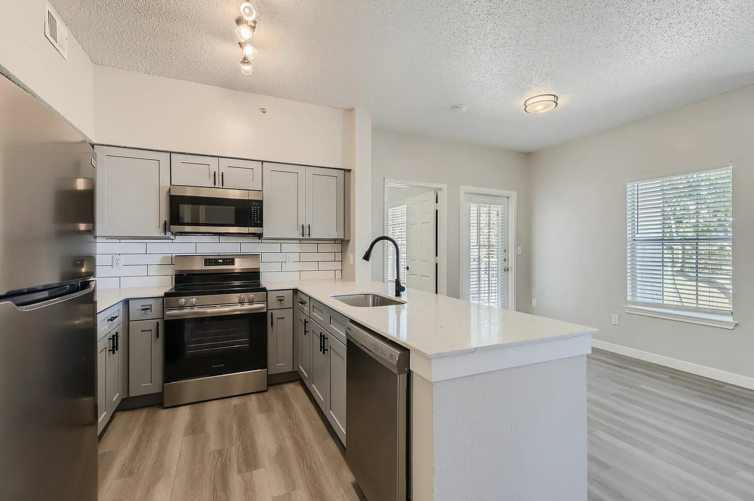 Kitchen, white countertops, stainless steel appliances, subway tile backsplash