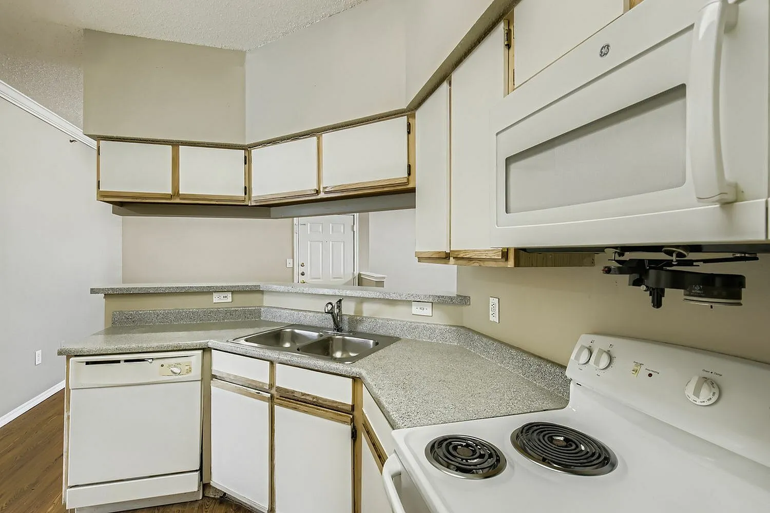 Kitchen sink, speckled countertop, wood-trim cabinetry