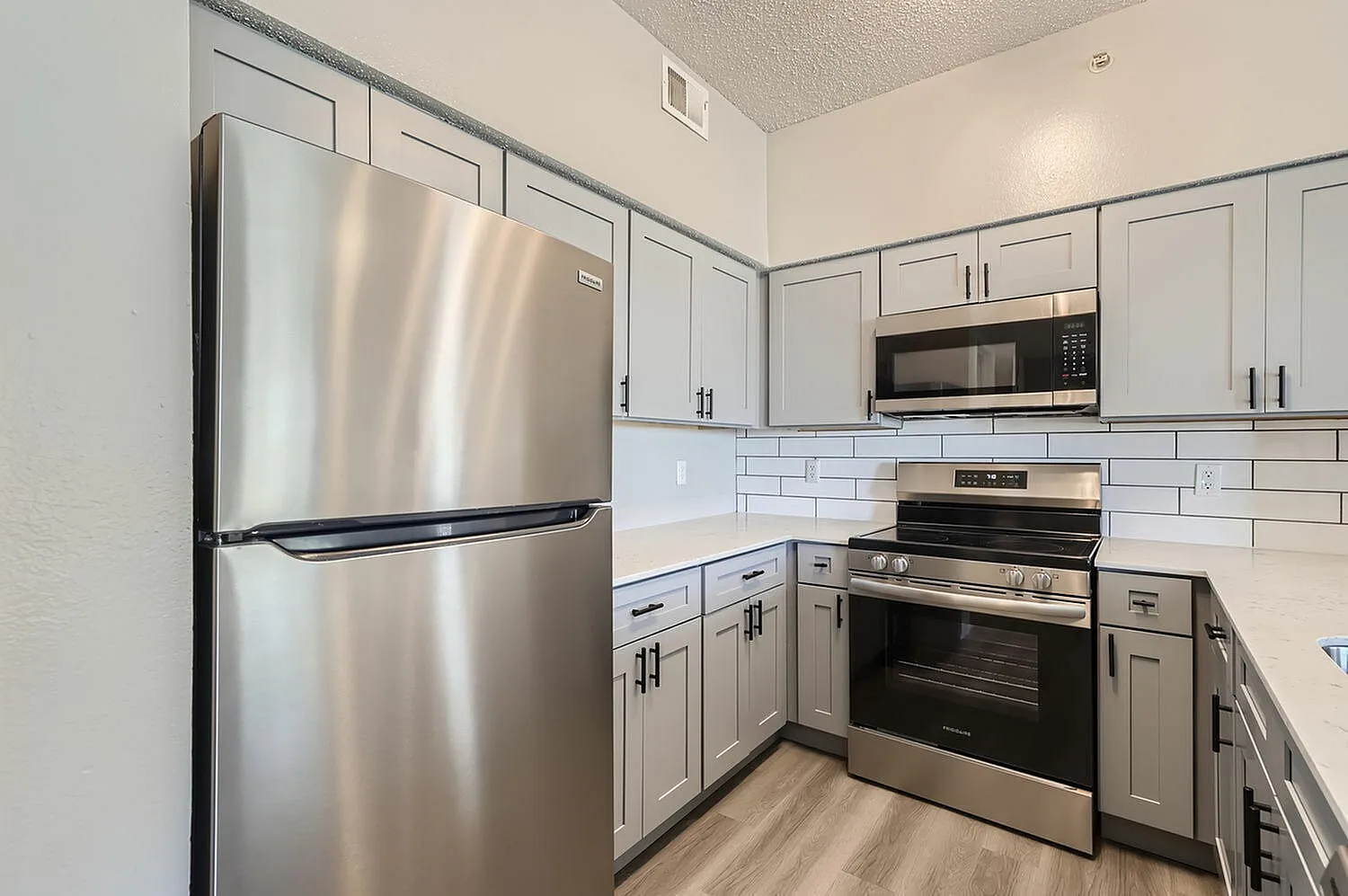 Stainless steel refrigerator, electric range, subway tile backsplash