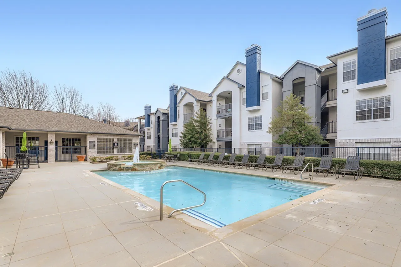 Community pool, lounge chairs, clubhouse building, pergola, mature trees