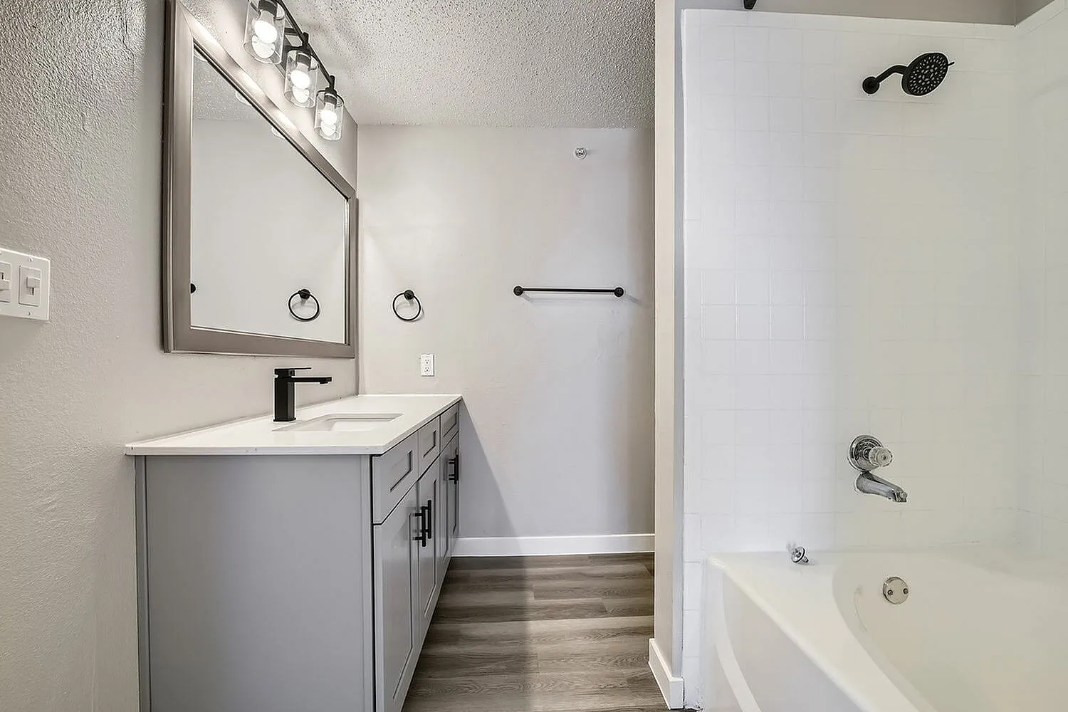 Bathroom vanity, framed mirror, gray cabinet, tub shower