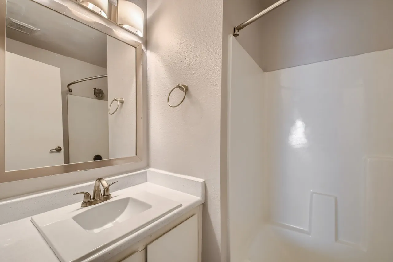 Bathroom, white vanity, framed mirror, glass shower enclosure