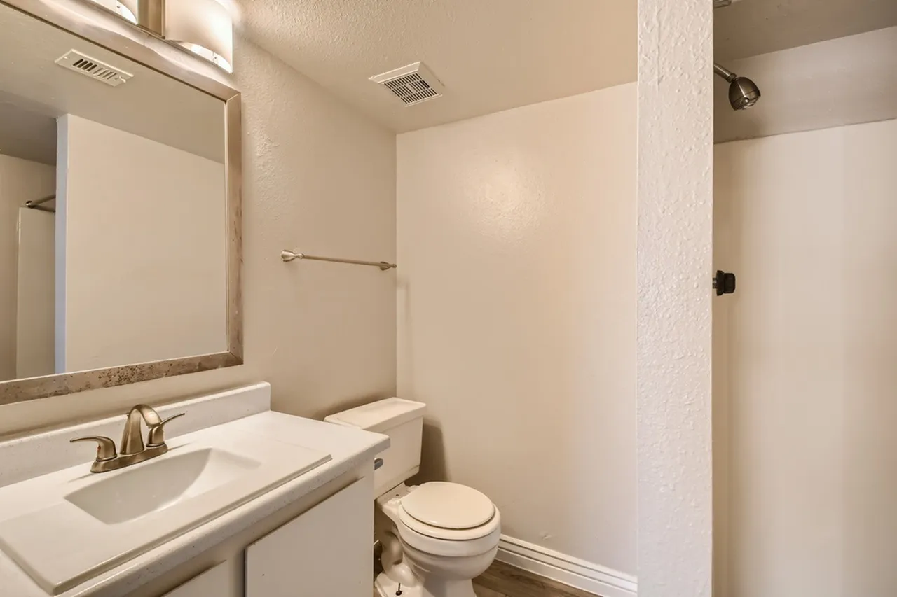Bathroom, white vanity with sink, framed mirror, toilet, shower enclosure