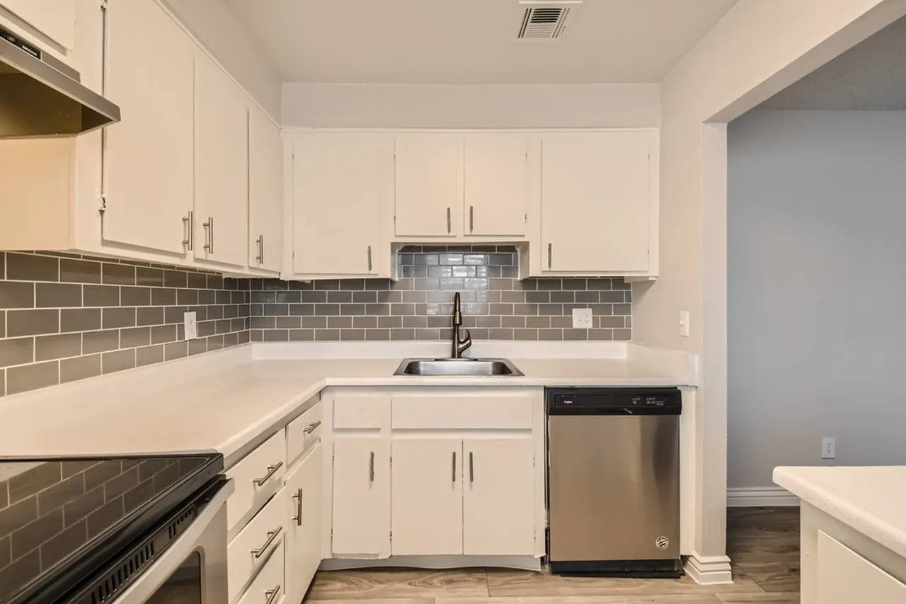 Kitchen, white shaker cabinetry, gray subway tile backsplash, quartz countertops, stainless appliances, wood-style plank flooring