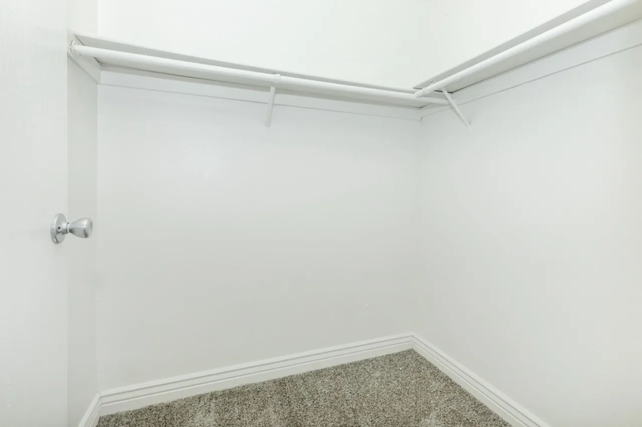 Closet, white walls, metal shelving, hanging rod, carpeted floor