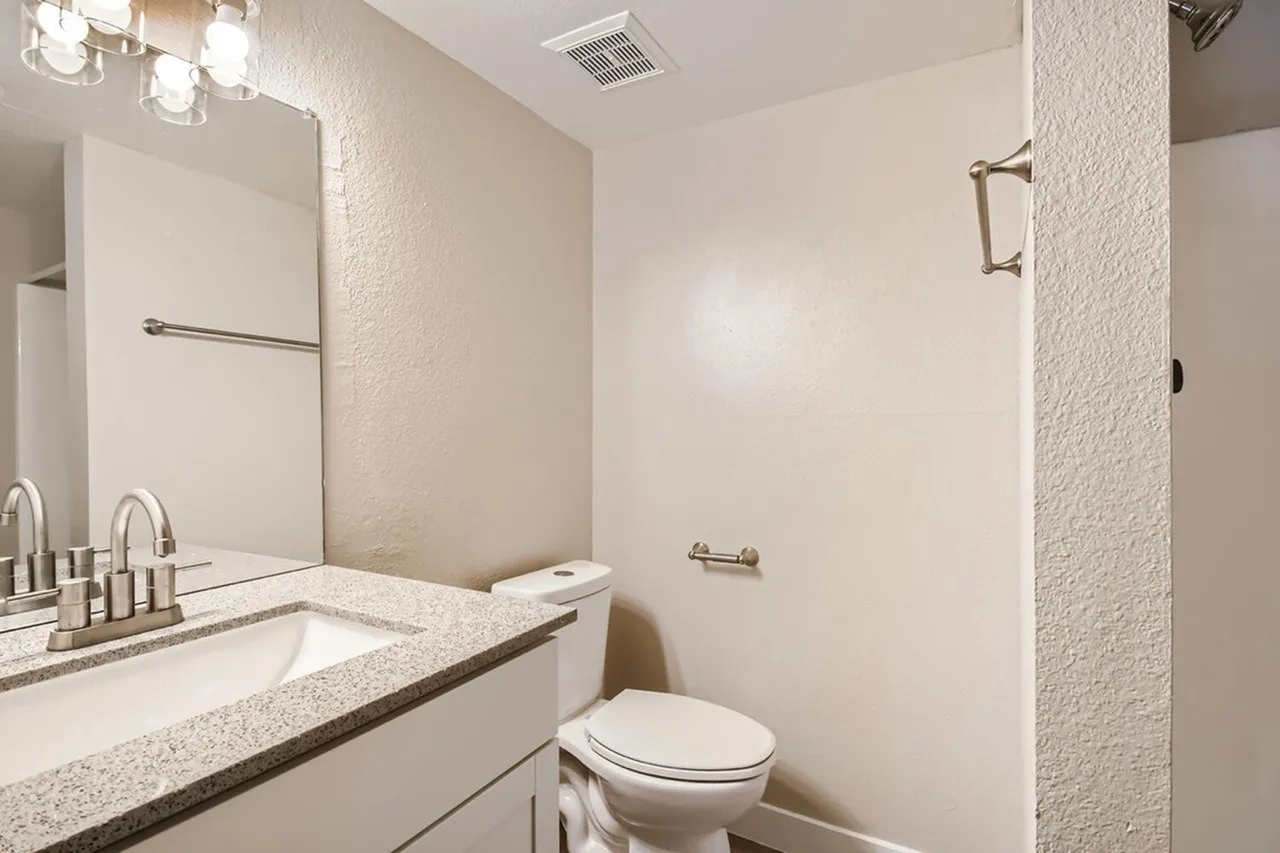 Bathroom, dual sink vanity with quartz countertops, chrome faucets, large mirror, toilet