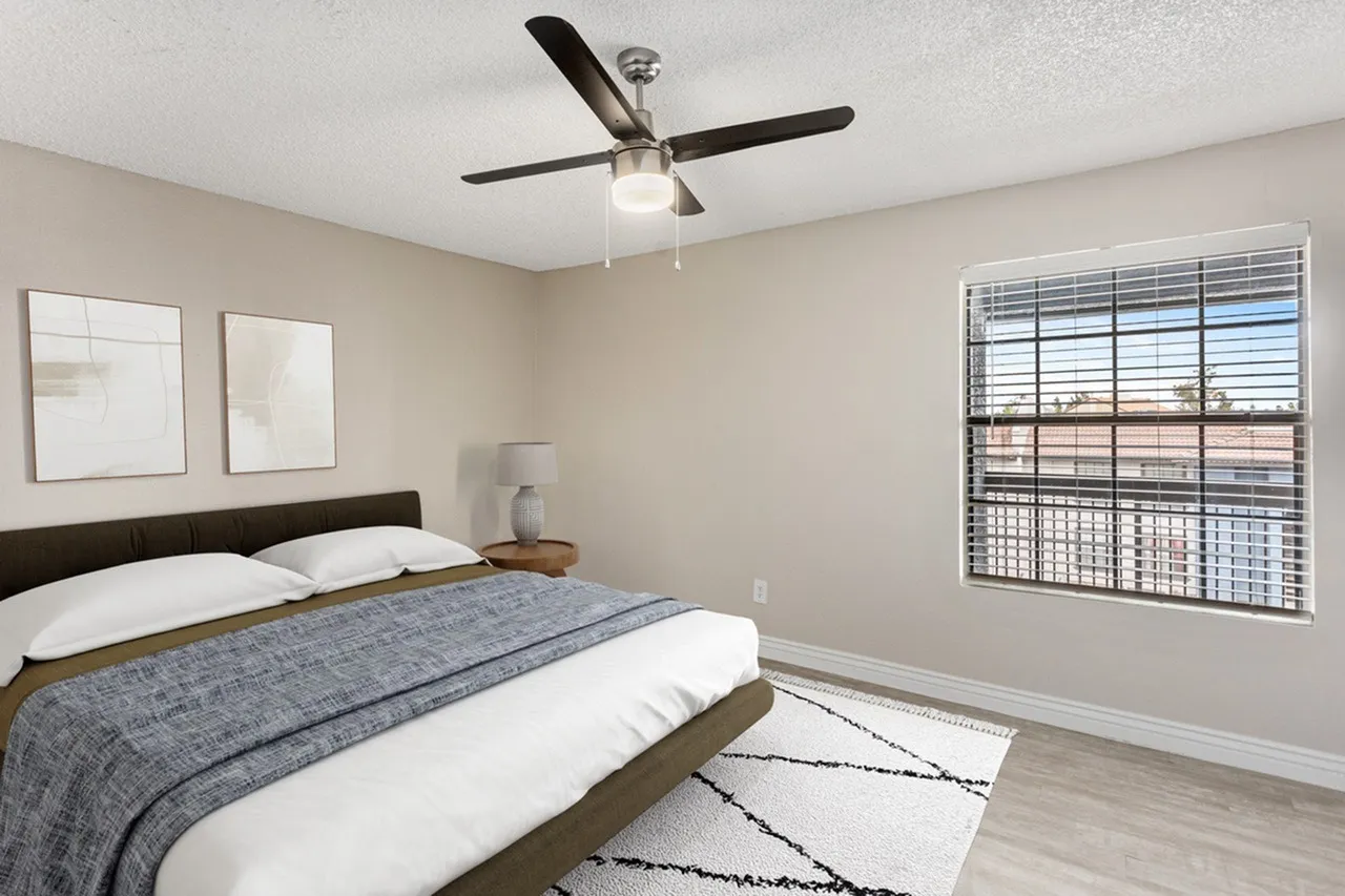 Primary bedroom, dark wood-frame bed, wood-style plank flooring, ceiling fan with light fixture