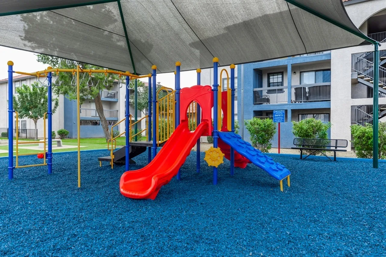 Outdoor playground, red and blue slide, monkey bars, blue rubber surfacing, shade structure