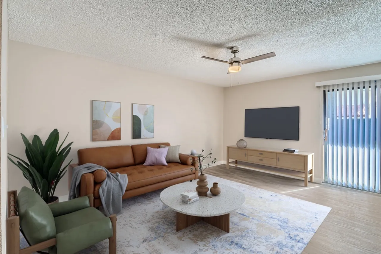 Living room, cognac leather sofa, wood-style plank flooring, ceiling fan, wall-mounted TV