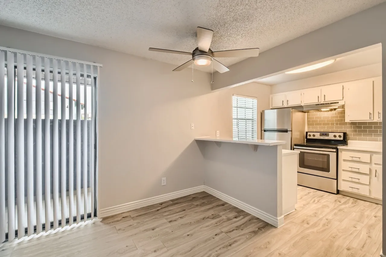 Kitchen and dining area, cream cabinetry, stainless steel appliances, wood-style plank flooring, ceiling fan
