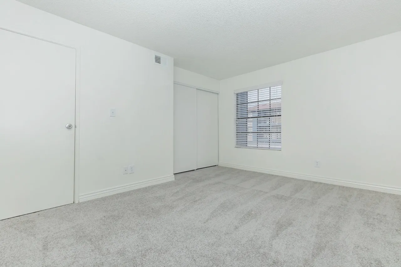 Bedroom, gray carpet flooring, sliding closet doors, louvered window