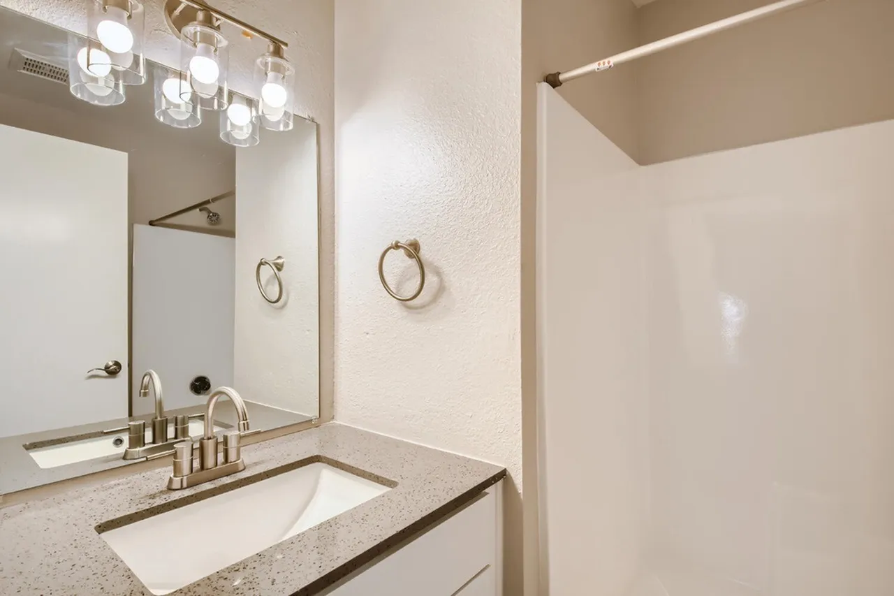Bathroom, quartz countertops, undermount sink, brass fixtures, framed mirror, pendant lighting