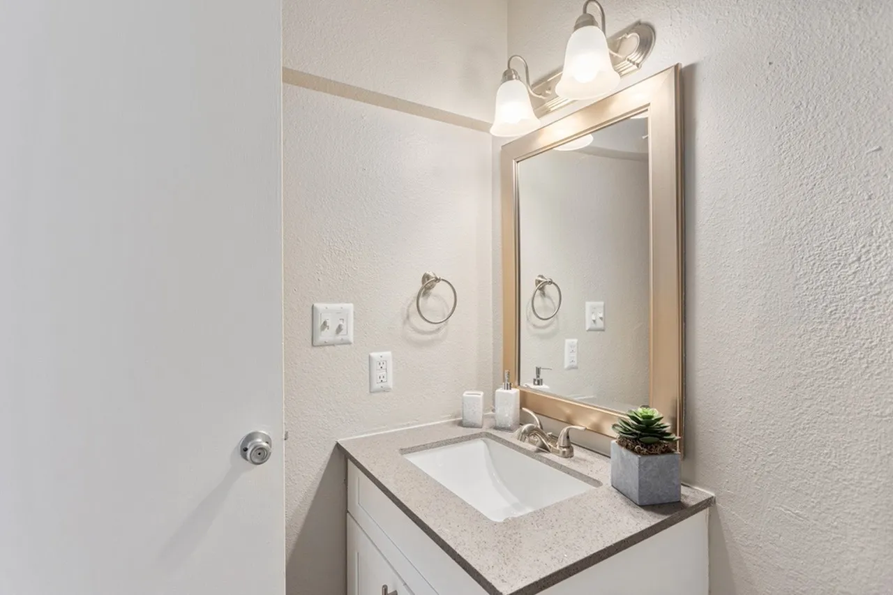 Bathroom, white vanity with quartz countertop, undermount sink, framed mirror with sconces