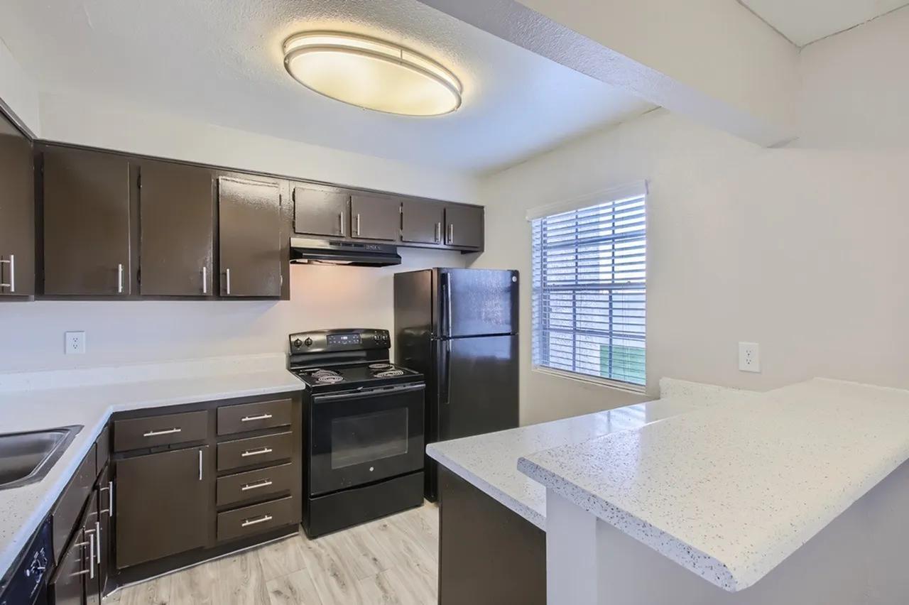Kitchen, dark cabinetry, quartz countertops, black stainless appliances, wood-style plank flooring