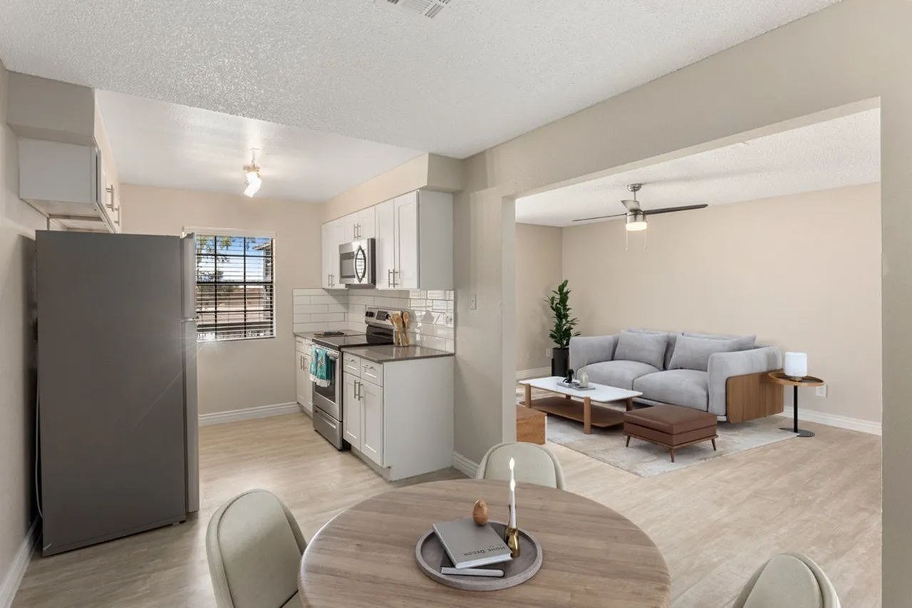 Open concept living area, wood-style plank flooring, white shaker cabinetry, stainless appliances, light gray sofa, dining table
