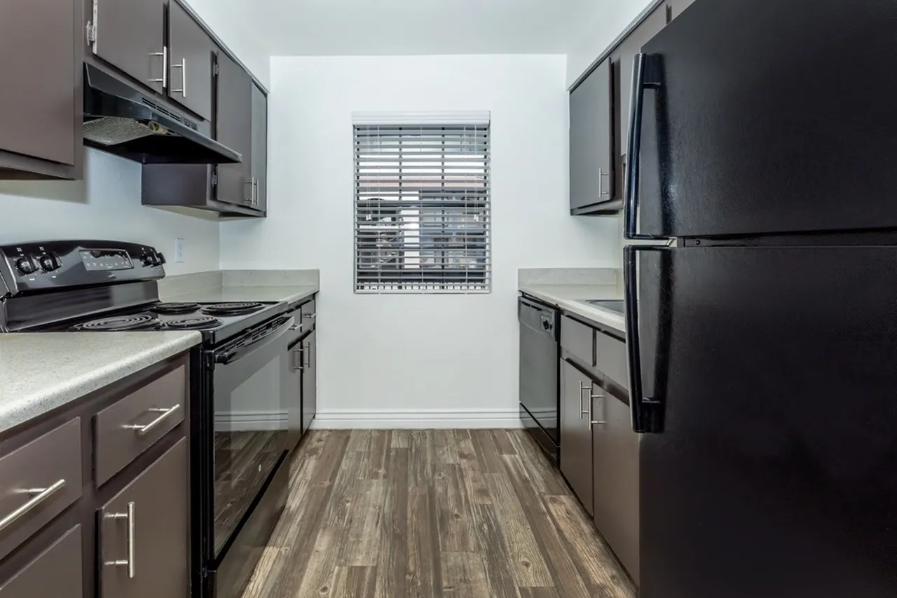 Kitchen, dark cabinetry, quartz countertops, stainless appliances, wood-style plank flooring