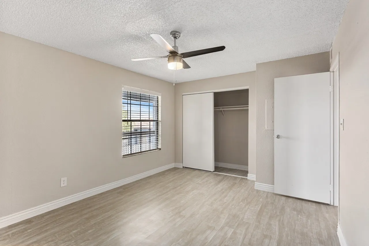 Primary bedroom, wood-style plank flooring, ceiling fan, closet doors