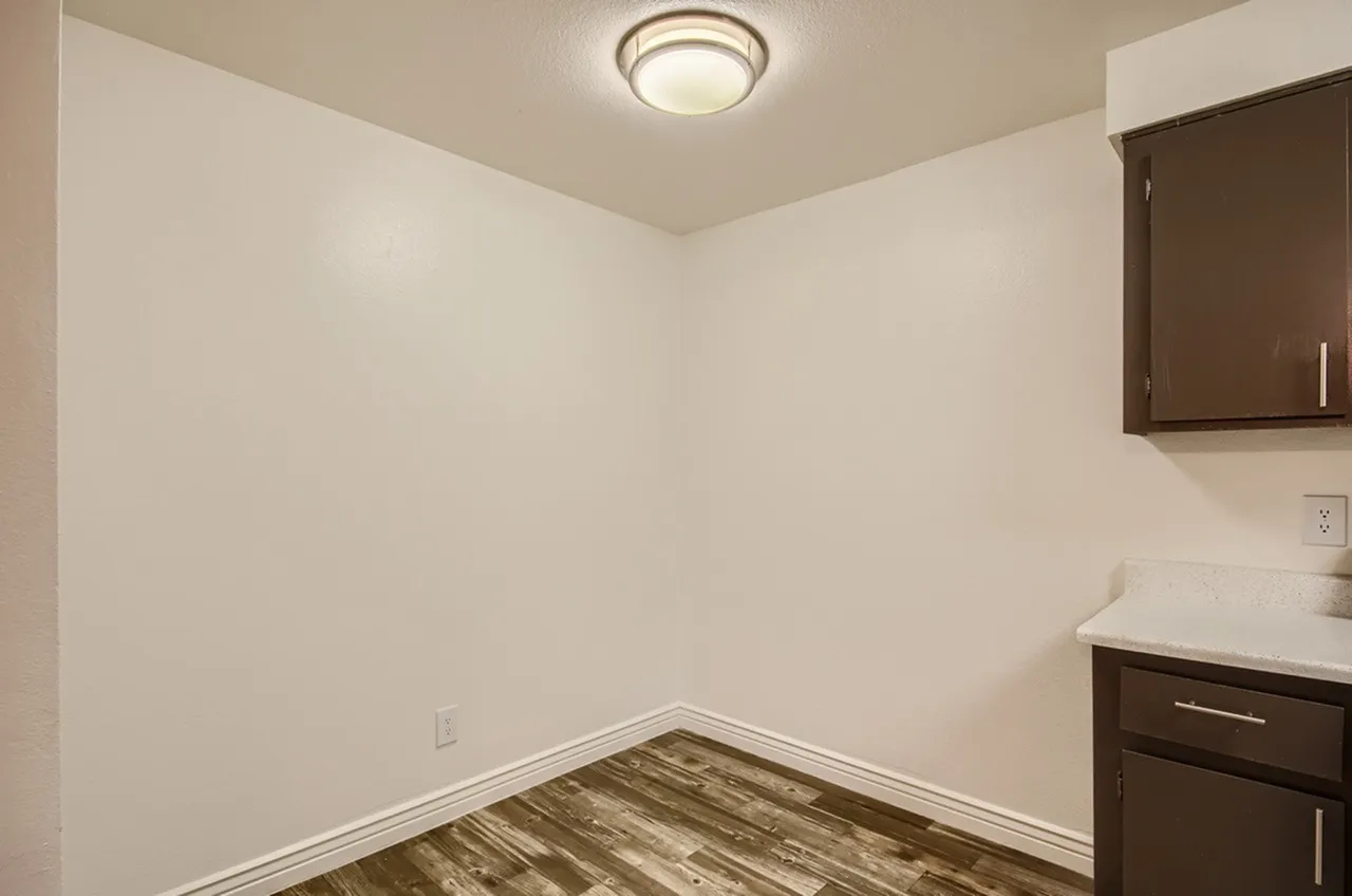 Laundry room, dark brown cabinetry, white countertop, wood-style plank flooring, recessed ceiling light