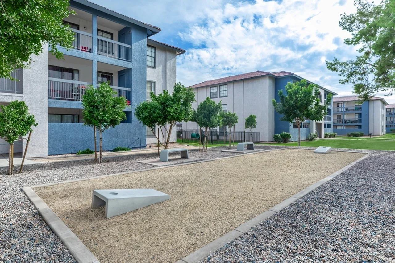 Exterior courtyard, gravel ground, young trees, concrete seating, apartment buildings