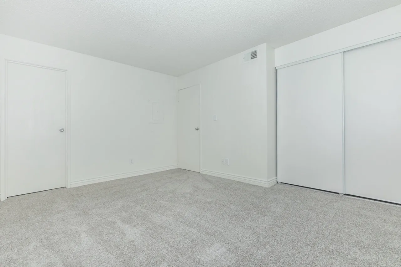 Bedroom, gray carpet flooring, white walls, sliding closet doors