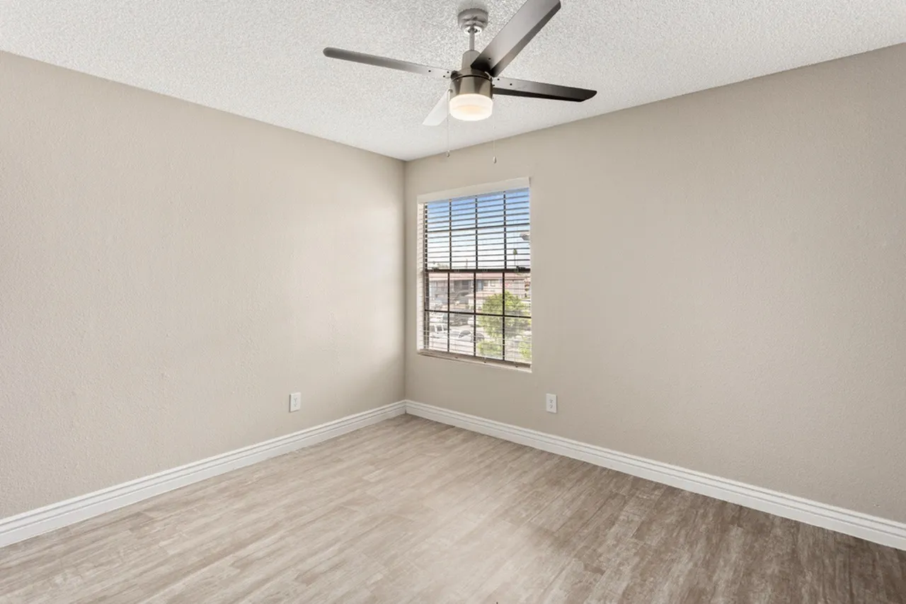 Bedroom, wood-style plank flooring, ceiling fan with light fixture, window with shutters