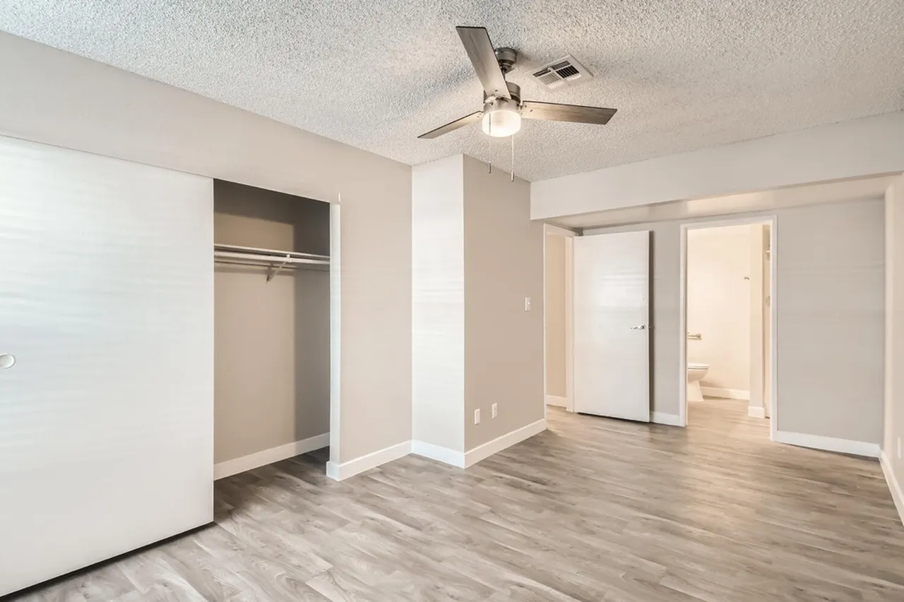 Bedroom, wood-style plank flooring, open closet, ceiling fan with light fixture, sliding glass doors