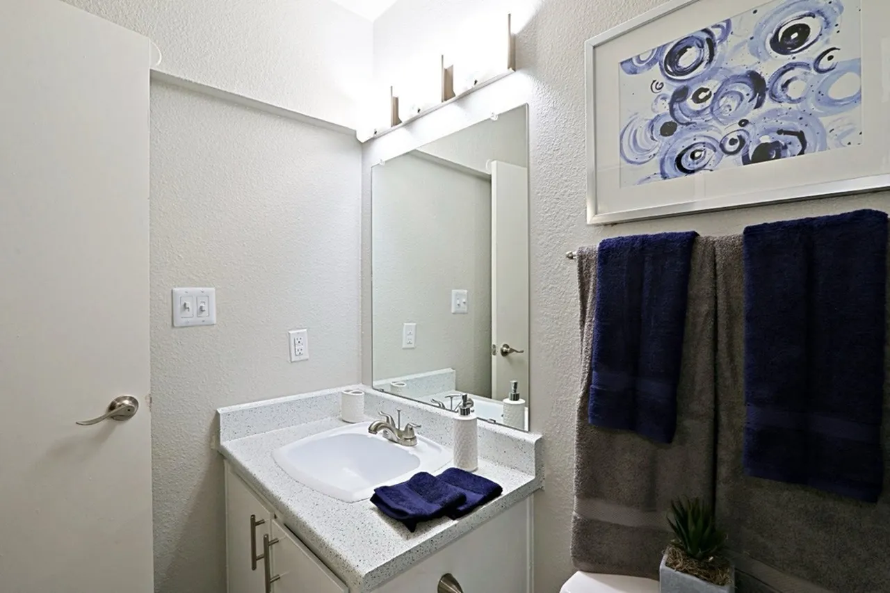 Bathroom, white quartz countertop, framed mirror, chrome faucet, dark blue towels