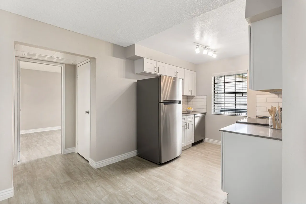 Kitchen, white shaker cabinetry, stainless appliances, wood-style plank flooring, breakfast bar with seating