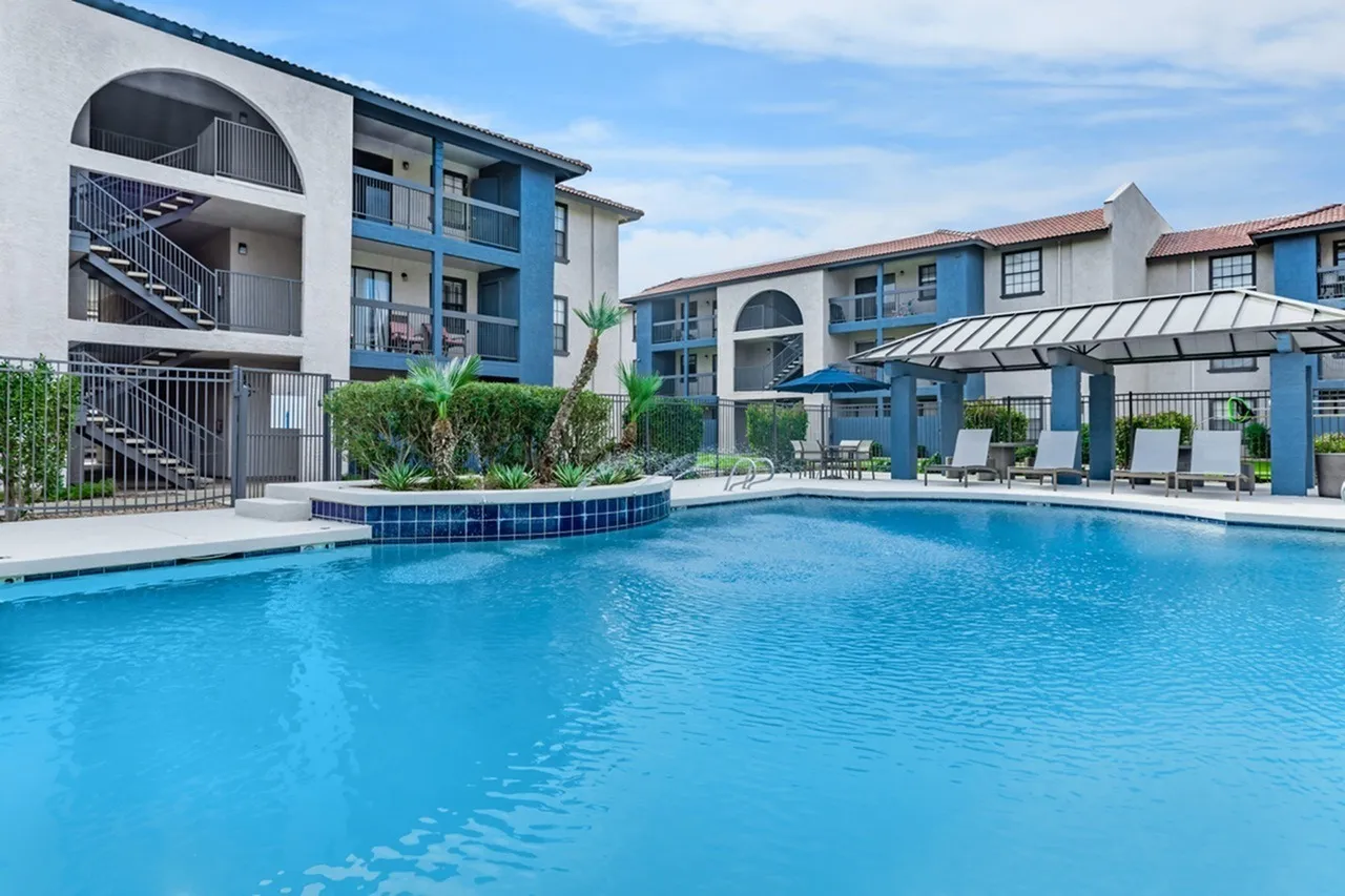 Resort-style pool, blue tile accents, palm landscaping, pergola lounge area