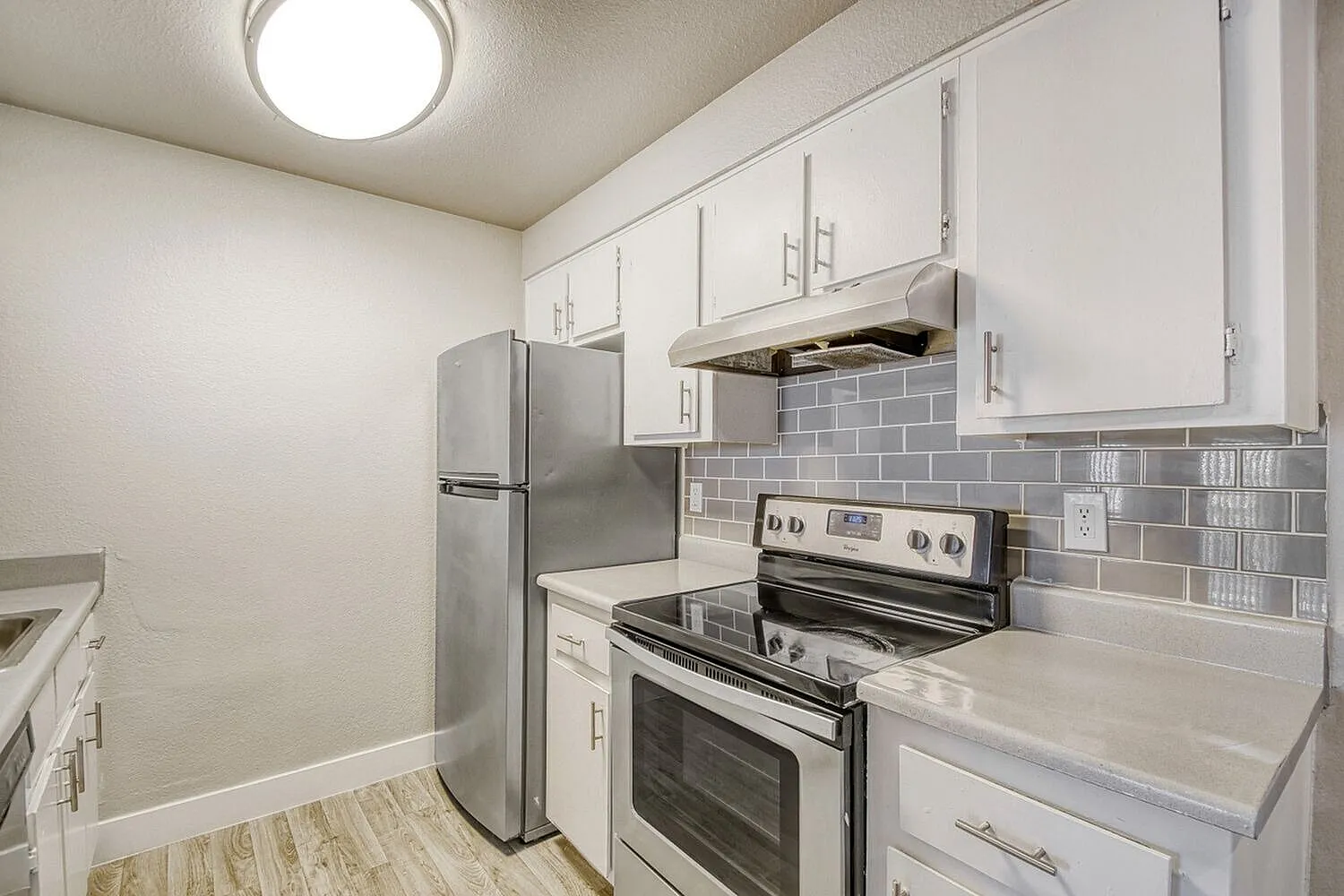 Kitchen, white shaker cabinetry, gray subway tile backsplash, stainless steel appliances, wood-style plank flooring