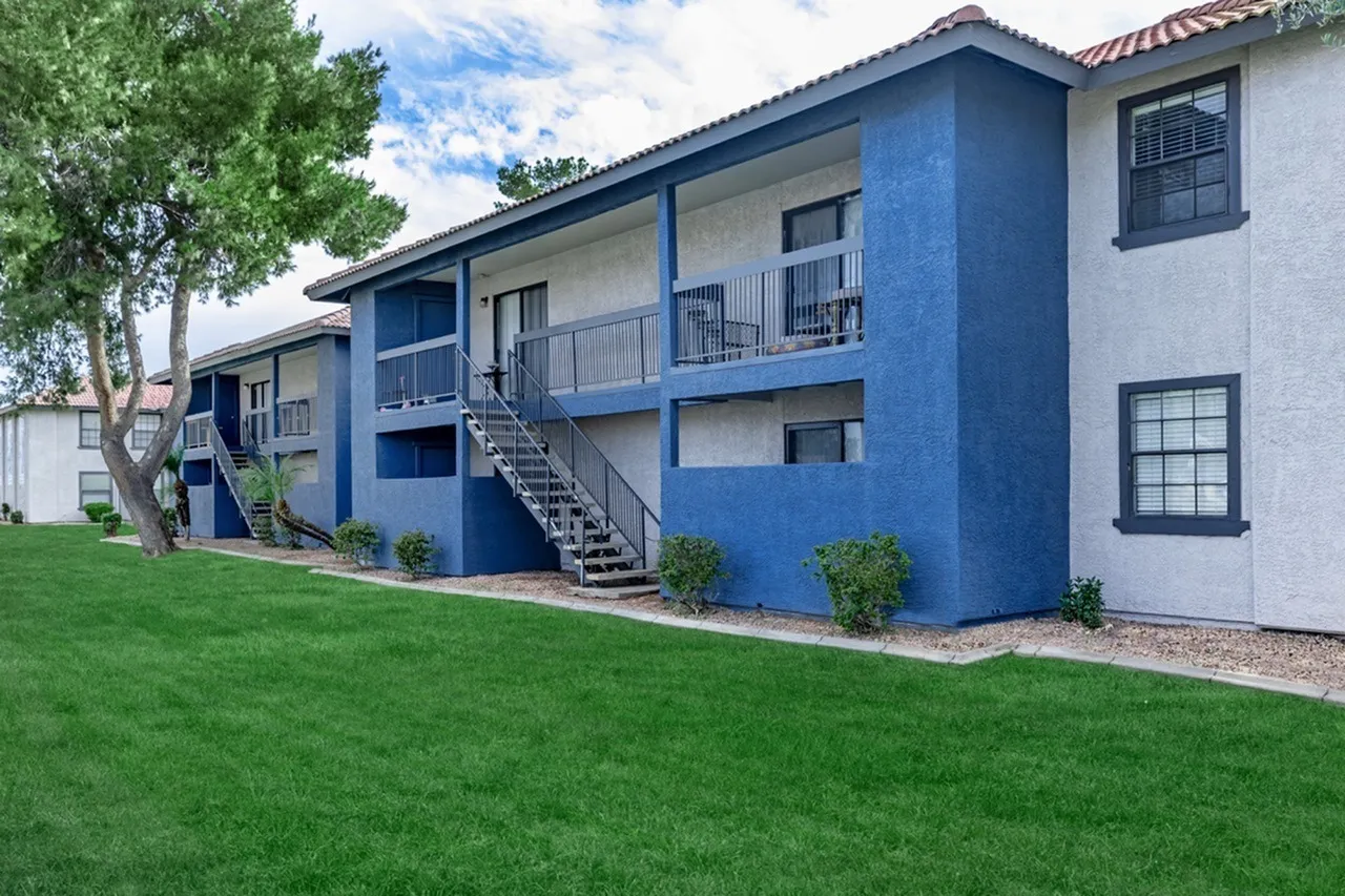 Apartment building exterior, blue and white facade, metal railings, landscaped lawn
