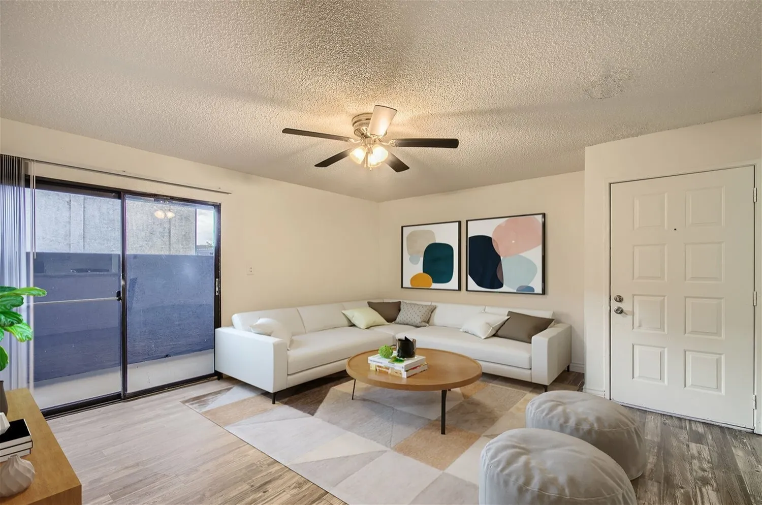Living room, cream sectional sofa, wood-style plank flooring, ceiling fan, glass patio doors