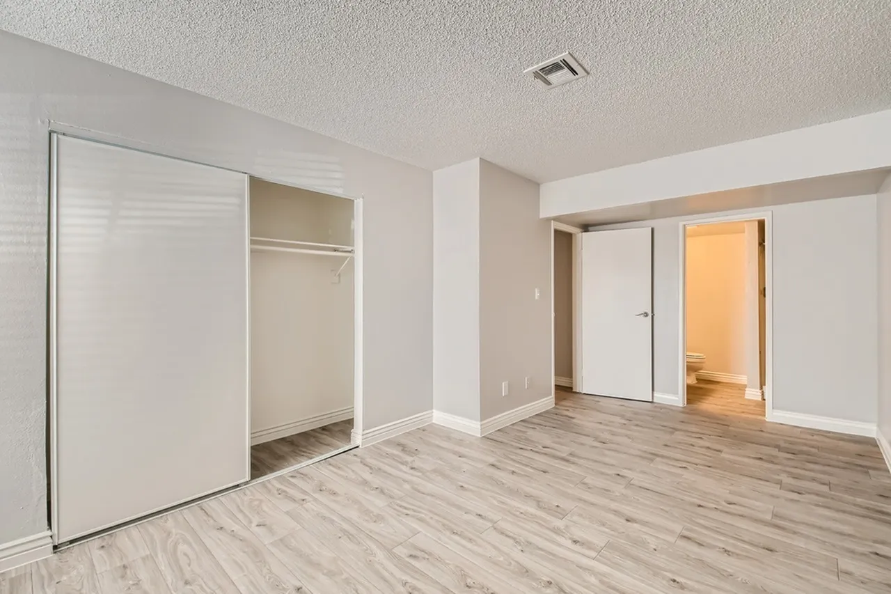 Primary bedroom, wood-style plank flooring, walk-in closet, white walls, recessed lighting