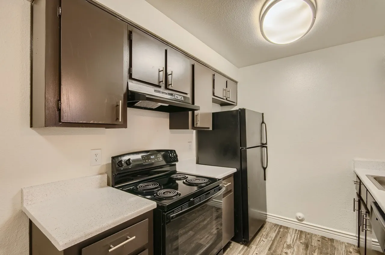 Kitchen, dark cabinetry, white quartz countertops, black electric range, stainless refrigerator, wood-style plank flooring