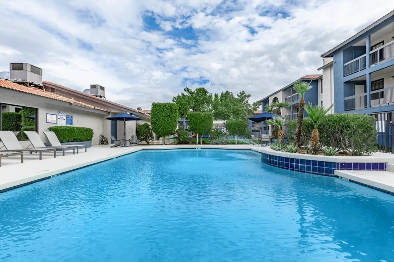 Resort-style swimming pool, lounge chairs, landscaping, residential buildings