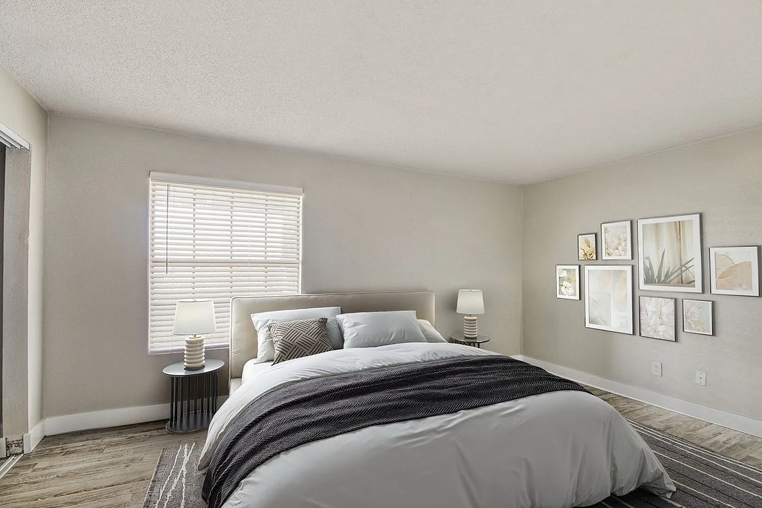 Primary bedroom, wood-style plank flooring, gray bed frame, white bedding, framed gallery wall