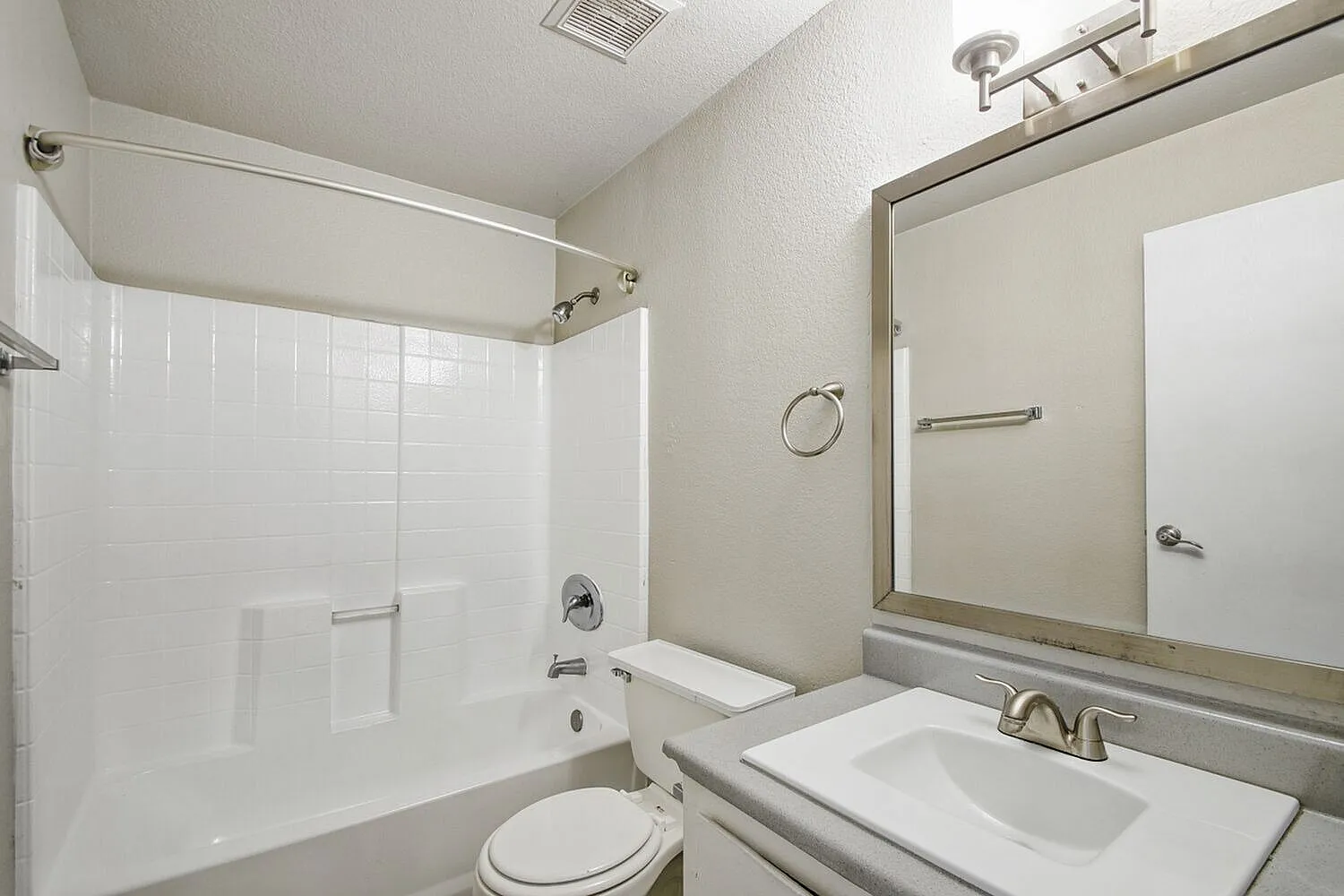 Bathroom, white vanity, framed mirror, white subway tile shower surround, toilet