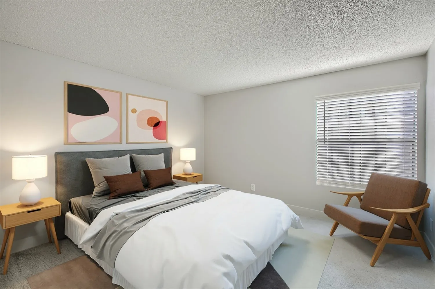 Primary bedroom, upholstered bed frame, wood-style nightstands, modern artwork, wood lounge chair, horizontal blinds