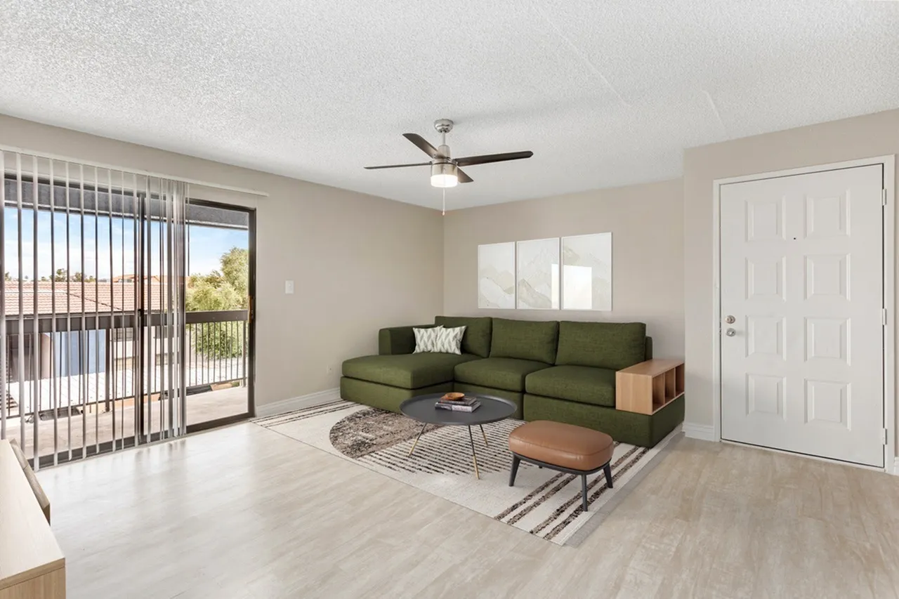 Living room, green sectional sofa, wood-style plank flooring, ceiling fan, glass balcony door
