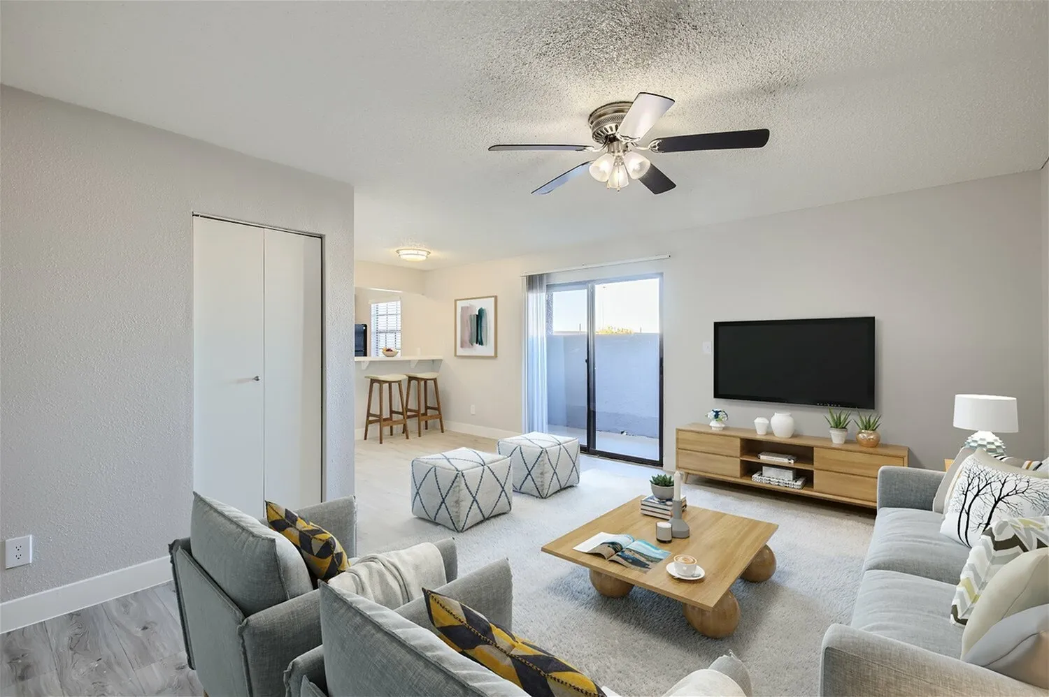 Living room with wood-style plank flooring, ceiling fan, gray upholstered furniture, glass sliding door