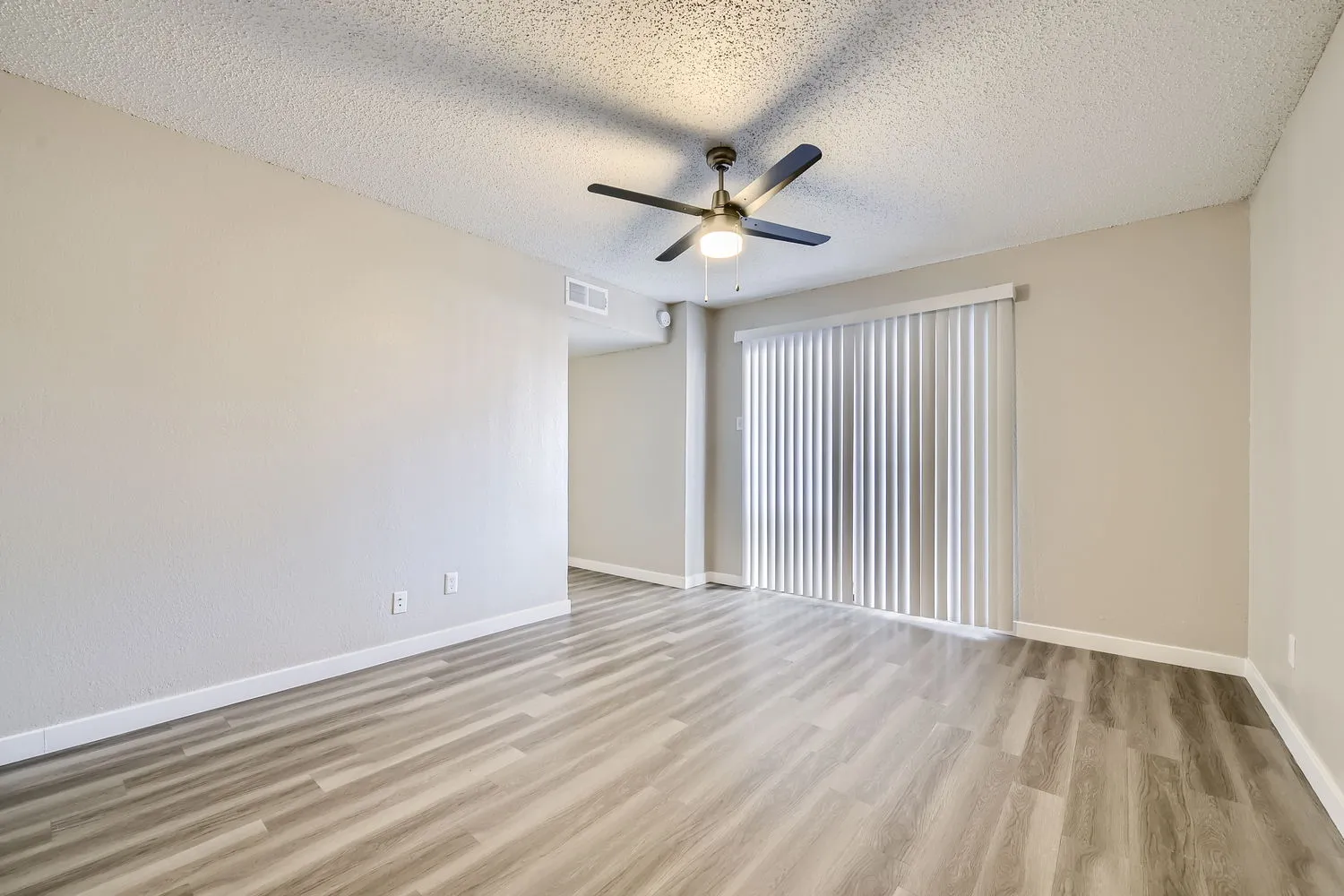 Primary bedroom with wood-style plank flooring, ceiling fan, sliding glass door