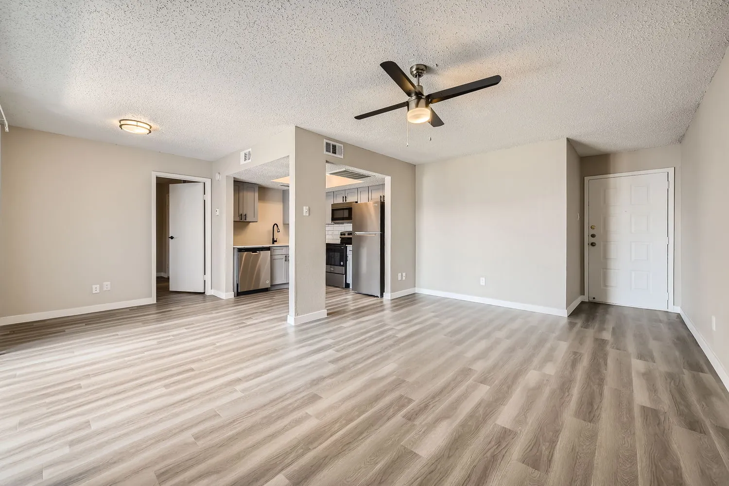 Living room, ceiling fan, entry door, open to kitchen