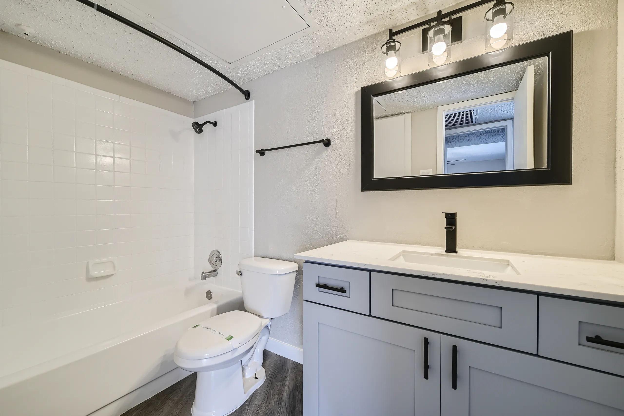 Primary bathroom with quartz vanity countertop, matte black fixtures, framed mirror, tub-shower combo
