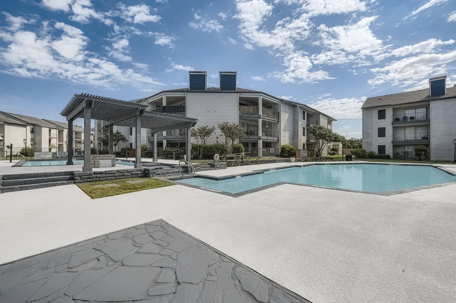 Community pool area with pergola, spa, and stone accents