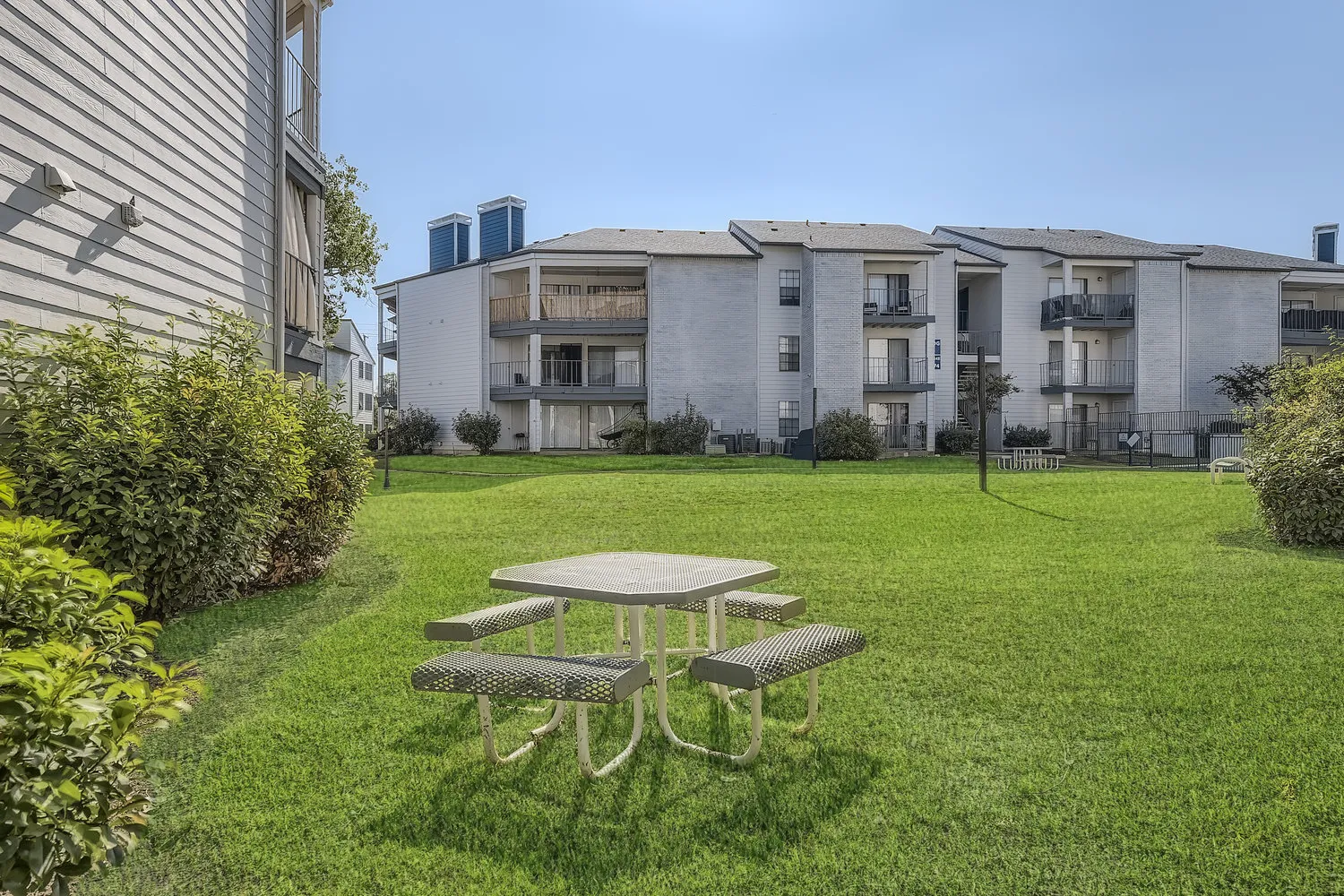 Green community lawn with picnic table, surrounded by residential buildings