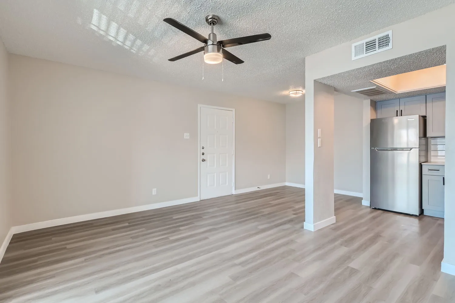 Living room, ceiling fan, entry door, open to kitchen