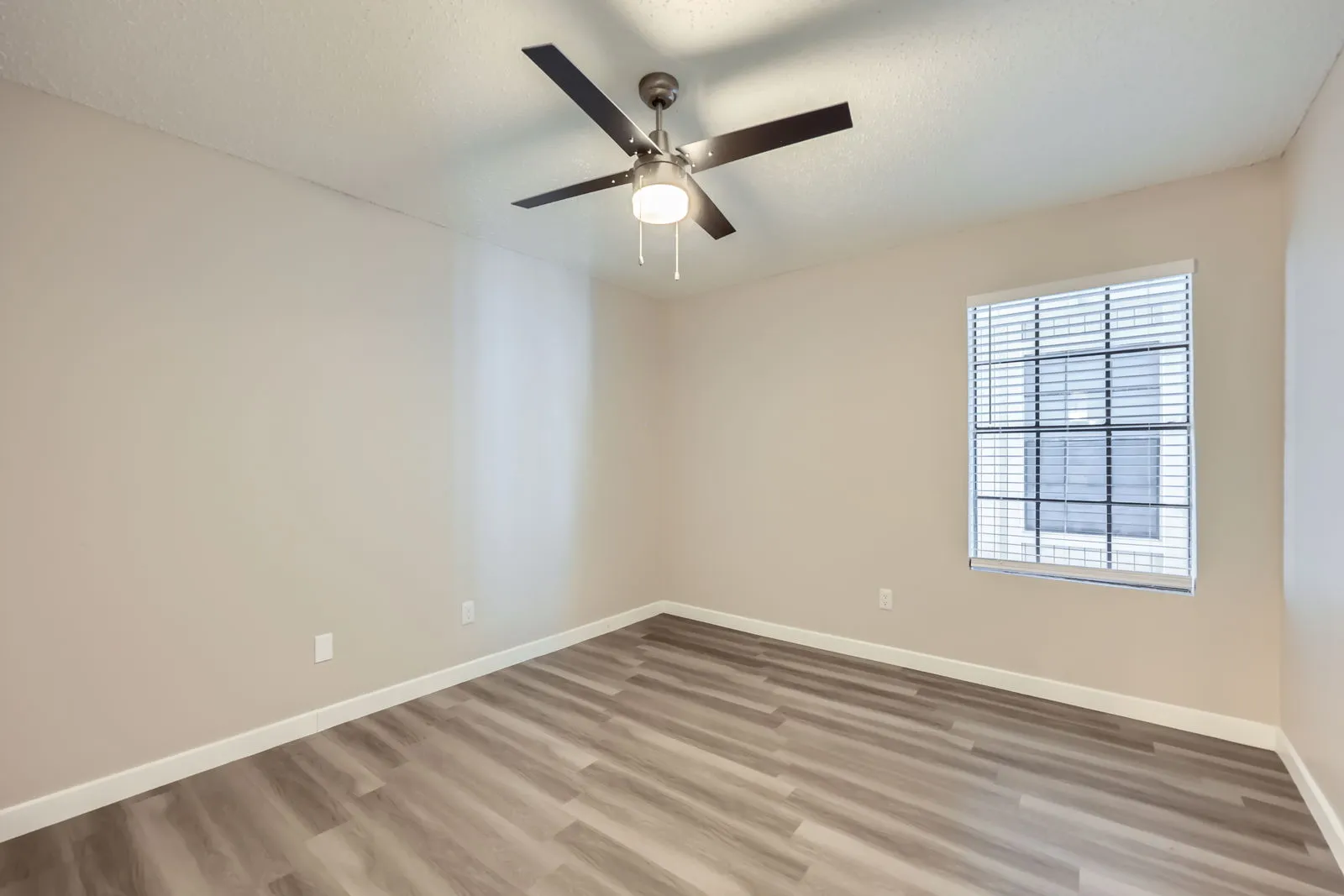 Bedroom with wood-style plank flooring, ceiling fan, large window with natural light