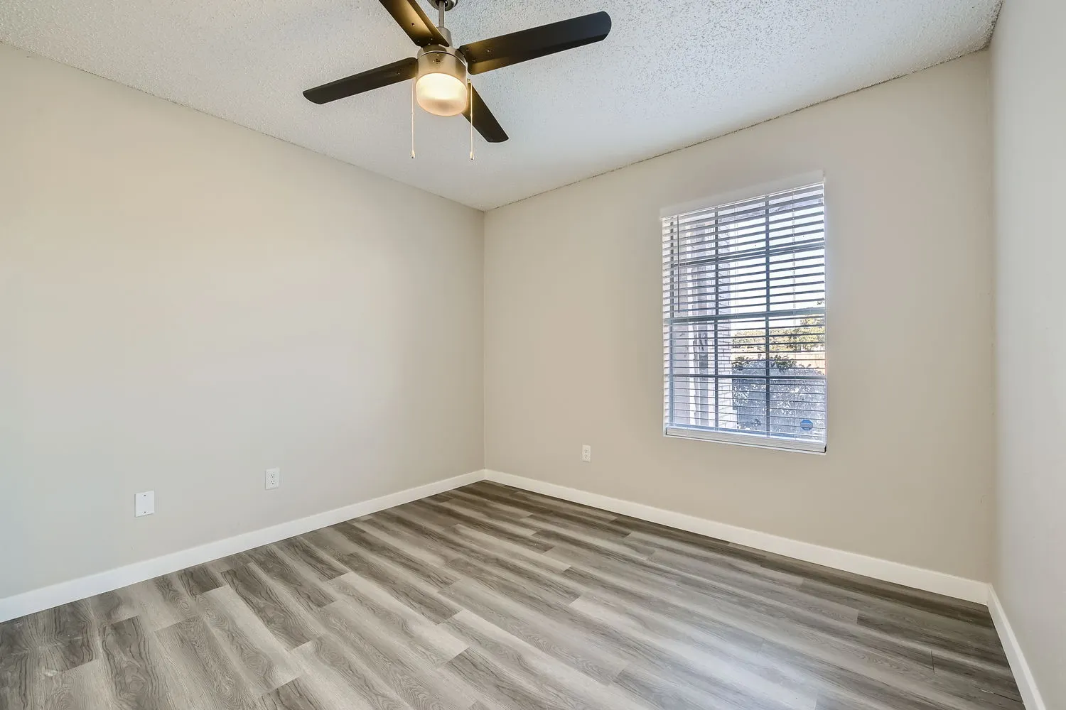 Primary bedroom, wood-style plank flooring, ceiling fan, window